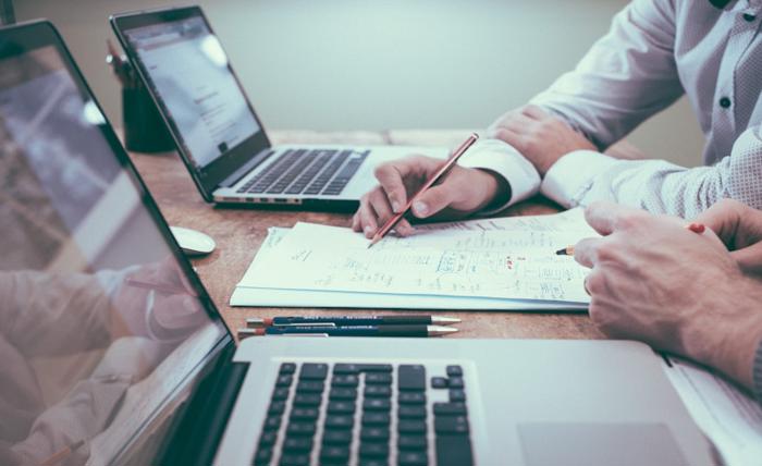 Two individuals working together on a laptop at a desk, engaged in knowledge management for the insurance industry