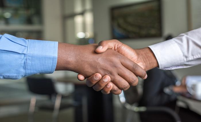 Two individuals in an office shaking hands, representing a partnership focused on enhancing customer satisfaction and retention
